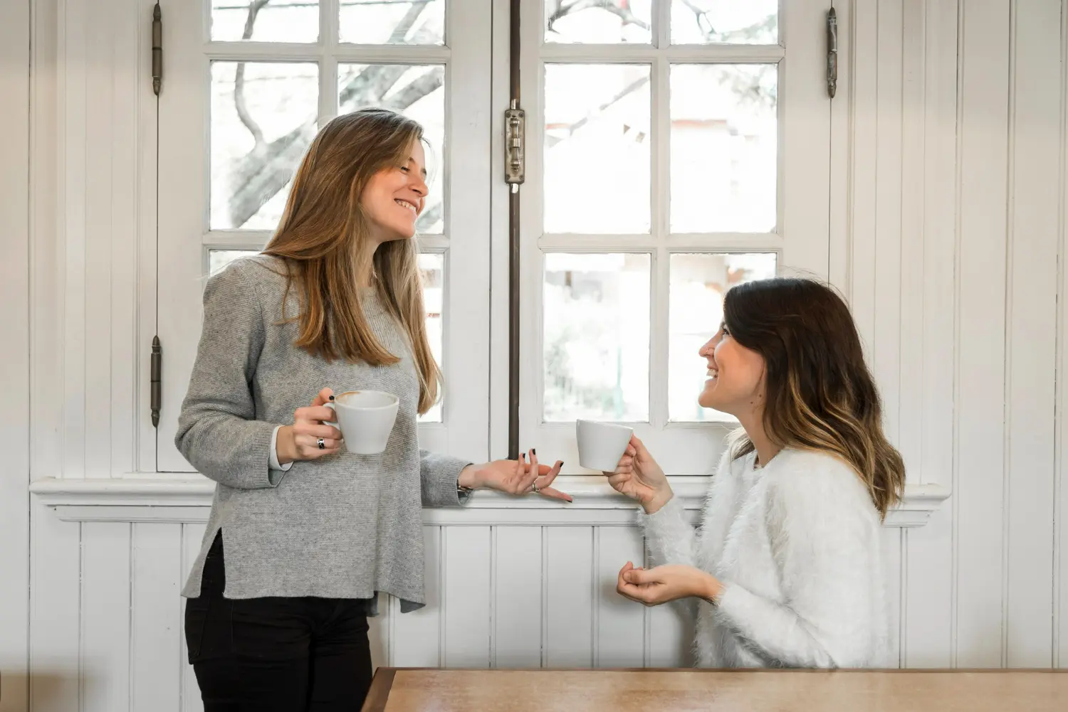 Two women talking over coffee, representing friendship and supportive relationships in recovery